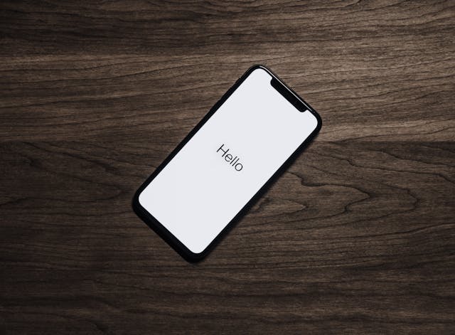  A phone on a wooden surface with “Hello” written on the screen